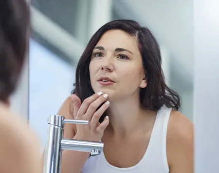 Mujer revisando su piel en el espejo 